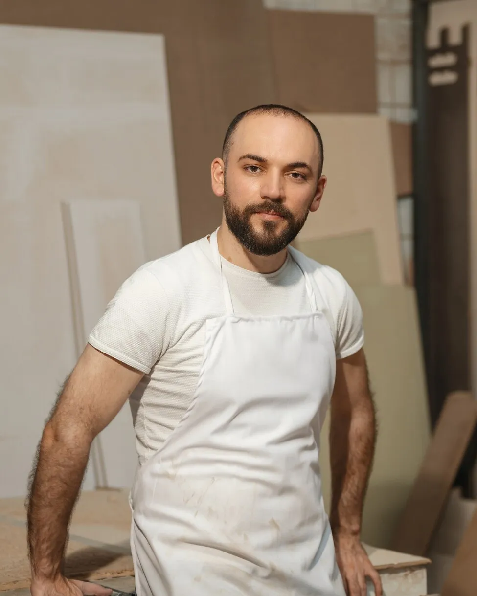 Rebal Jber in the workshop, wearing a white apron